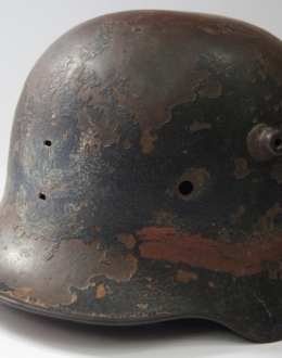 Helm vom Warschauer Aufstand mit einem sichtbaren handbemalten um einen weißen und roten Streifen und einem weißen Adler an seiner Front.