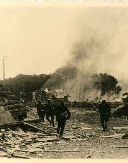 Żołnierze niemieccy na Westerplatte, w tle płonące składy Rady Portu i Dróg Wodnych na Westerplatte. 1 września 1939 r.