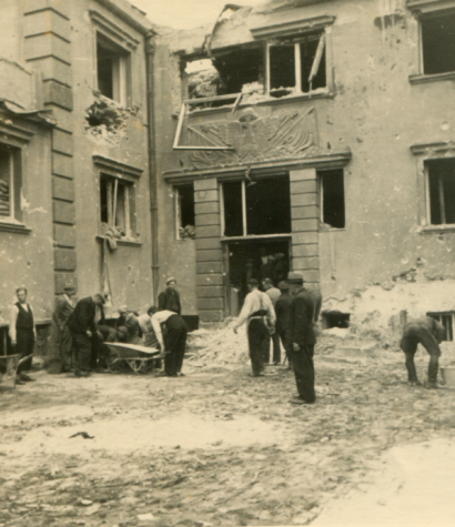 Archiwalna fotografia nowych koszar na Westerplatte. Zdjęcie wykonano po kapitulacji polskich obrońców. Na fotografii widać jeńców cywilnych porządkujących wnętrze koszar i teren przy głównym wejściu do budynku.