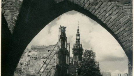 Na fotografii widoczne ruiny Bramy Chlebnickiej, w tle widać wieżę Ratusza oraz wieżę Kościoła Mariackiego.