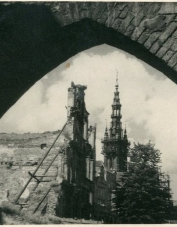 Na fotografii widoczne ruiny Bramy Chlebnickiej, w tle widać wieżę Ratusza oraz wieżę Kościoła Mariackiego.