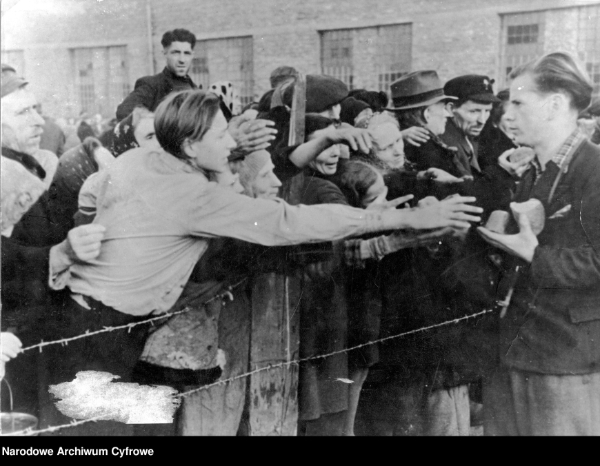 Rozdawanie chleba mieszkańcom Warszawy, którzy trafili do obozu przejściowego Dulag 121 w Pruszkowie. Wrzesień 1944 r. (NAC)