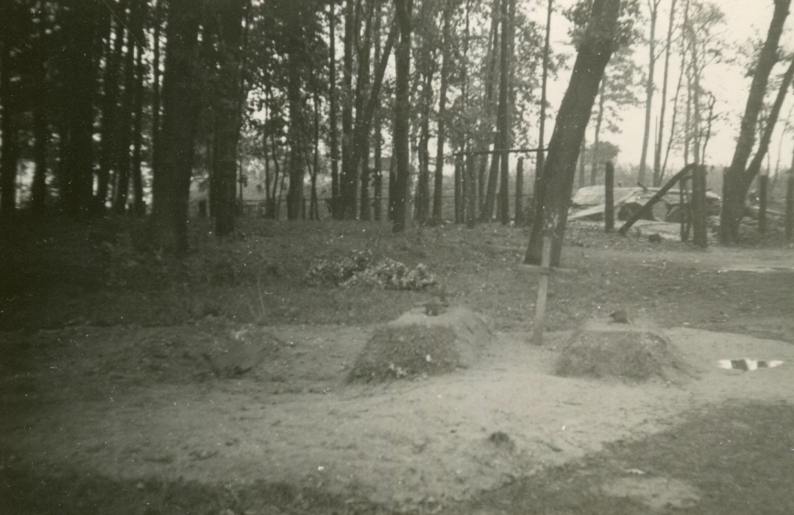 Trzy kopczyki grobowe wskazujące miejsca pochówków poległych polskich obrońców, widok w kierunku północno-wschodnim. Fotografia wykonana po 7 września 1939 r. W tle widoczne drzewa, dzięki którym możliwe było ustalenie lokalizacjo mogił, na dalszym planie ruiny wartowni nr 5. 