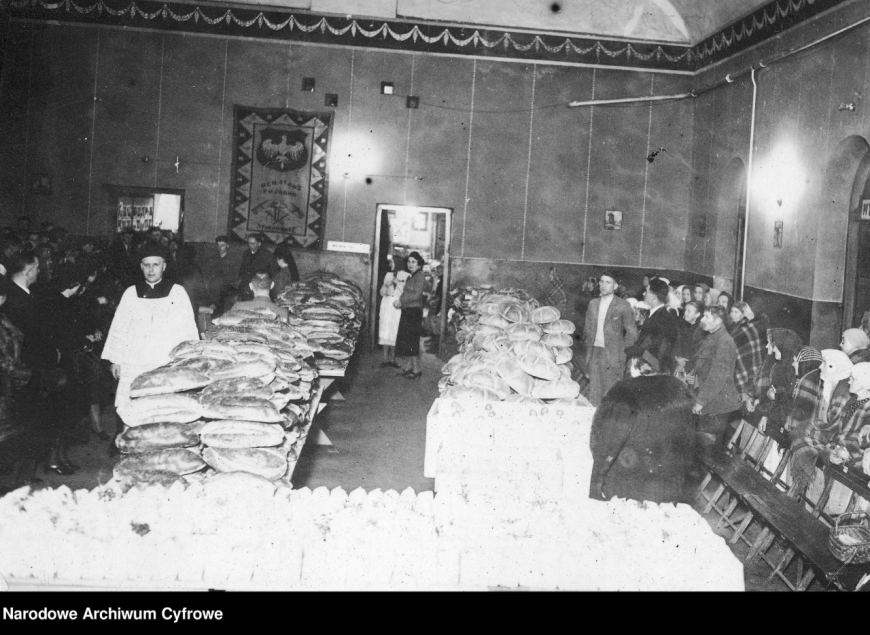 Starachowice. Fragment spotkania świątecznego. Na stołach widoczne paczki żywnościowe przygotowane dla rodzin bezrobotnych. Grudzień 1943 r. (NAC)
