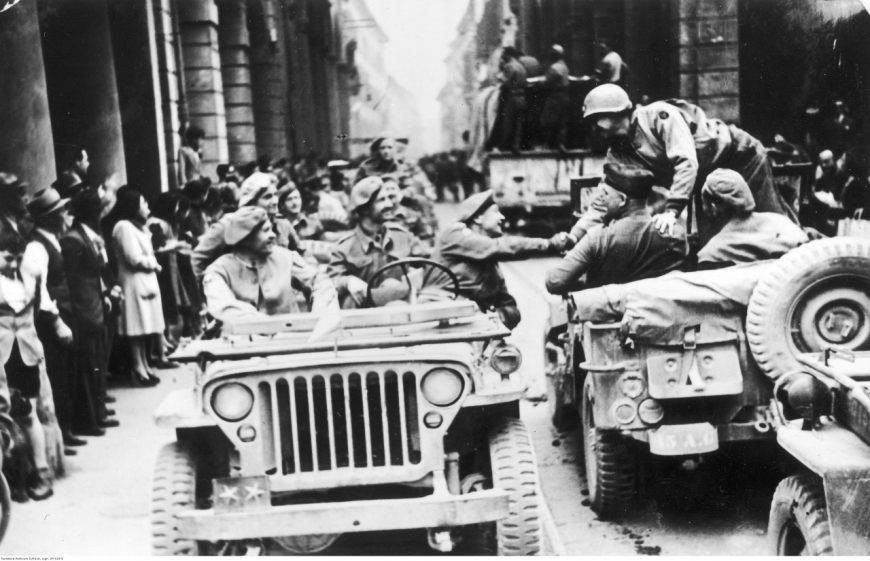 Wkroczenie wojsk polskich do Bolonii. Generał Klemens Rudnicki (za kierownicą) podaje rękę gen. Markowi Clarkowi. Na przednim siedzeniu siedzi gen. Zygmunt Szyszko-Bohusz. Bolonia, 21 IV 1945 r. (NAC)