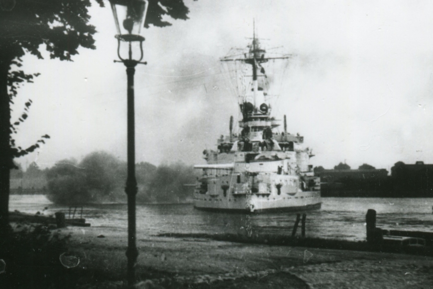 Jedna z wielu propagandowych fotografii ukazująca ostrzał Westerplatte z zakrętu Pięciu Gwizdków w dniu rozpoczęcia wojny z Polską. Ujęcie pokazuje rufę okrętu w momencie prowadzenia ognia z najcięższych dział oraz lewoburtowe działa artylerii średniego kalibru. 1 września 1939 r., autor nieznany (MIIWŚ)