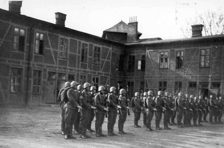 Plac apelowy wraz z polskimi żołnierzami w trakcie musztry. Na drugim planie widoczne obie elewacje budynku starych koszar. Autor nieznany, początek 1939 r. (CAW)