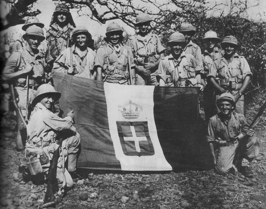 Żołnierze południowoafrykańscy ze zdobyczną flagą włoską, Moyale, marzec 1941 r., domena publiczna