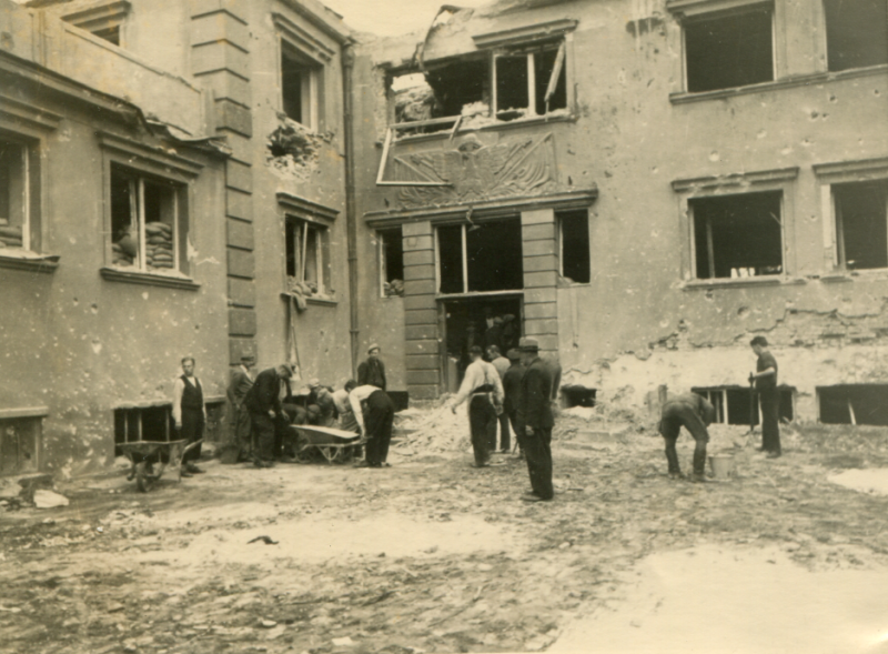 Archiwalna fotografia nowych koszar na Westerplatte. Zdjęcie wykonano po kapitulacji polskich obrońców. Na fotografii widać jeńców cywilnych porządkujących wnętrze koszar i teren przy głównym wejściu do budynku.